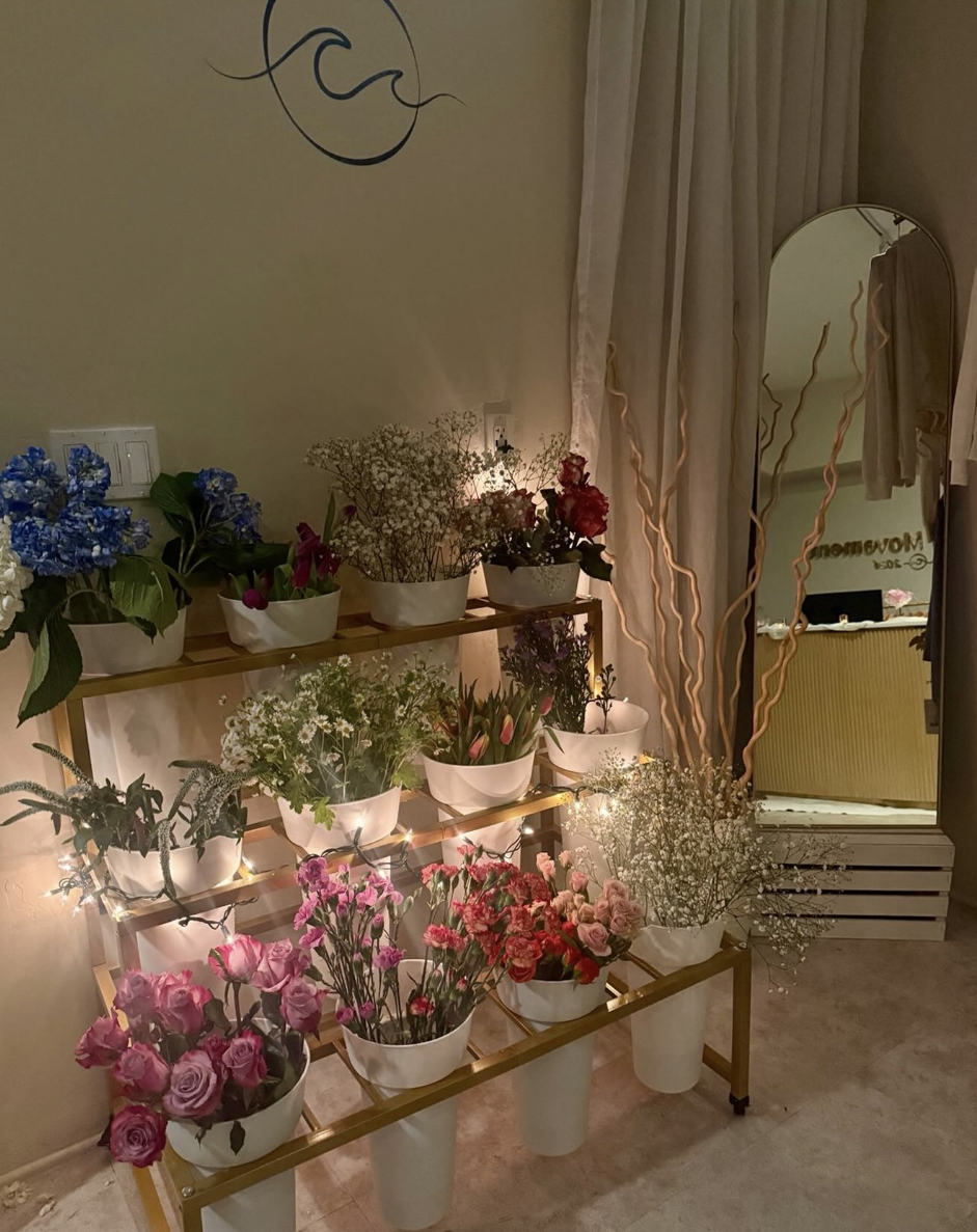 Gold floral cart filled with roses, hydrangeas and baby's breath beside an arched mirror