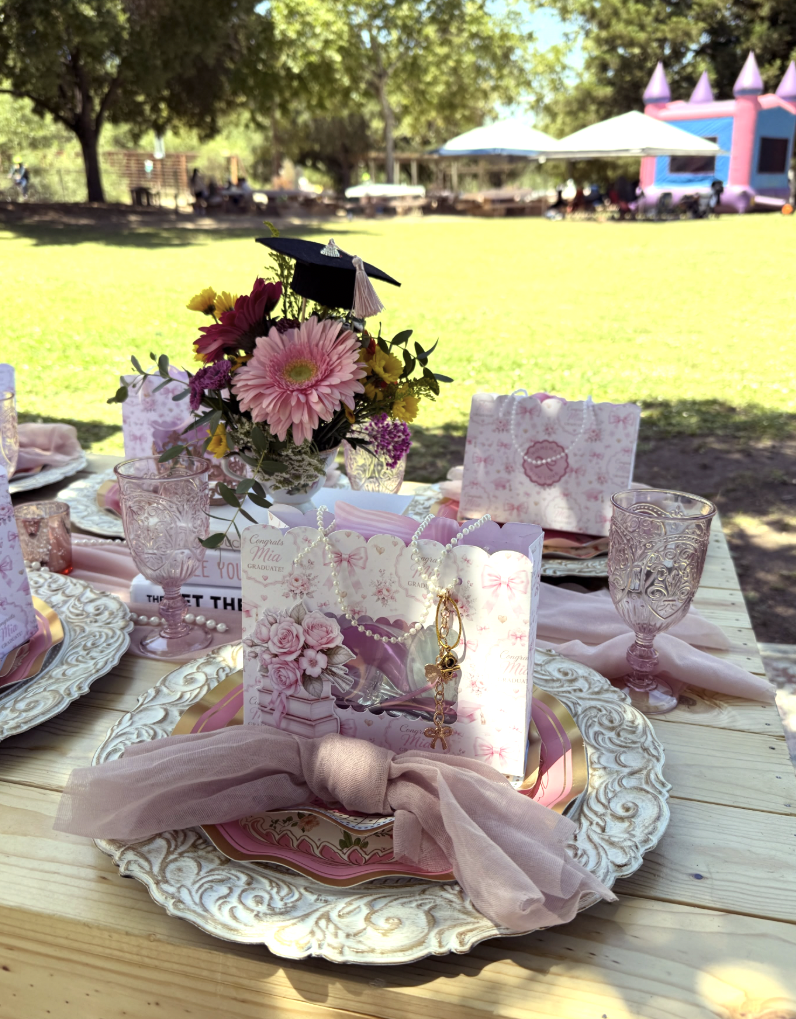 Graduation place setting with blush tulle, pearls and a floral centerpiece with a grad cap