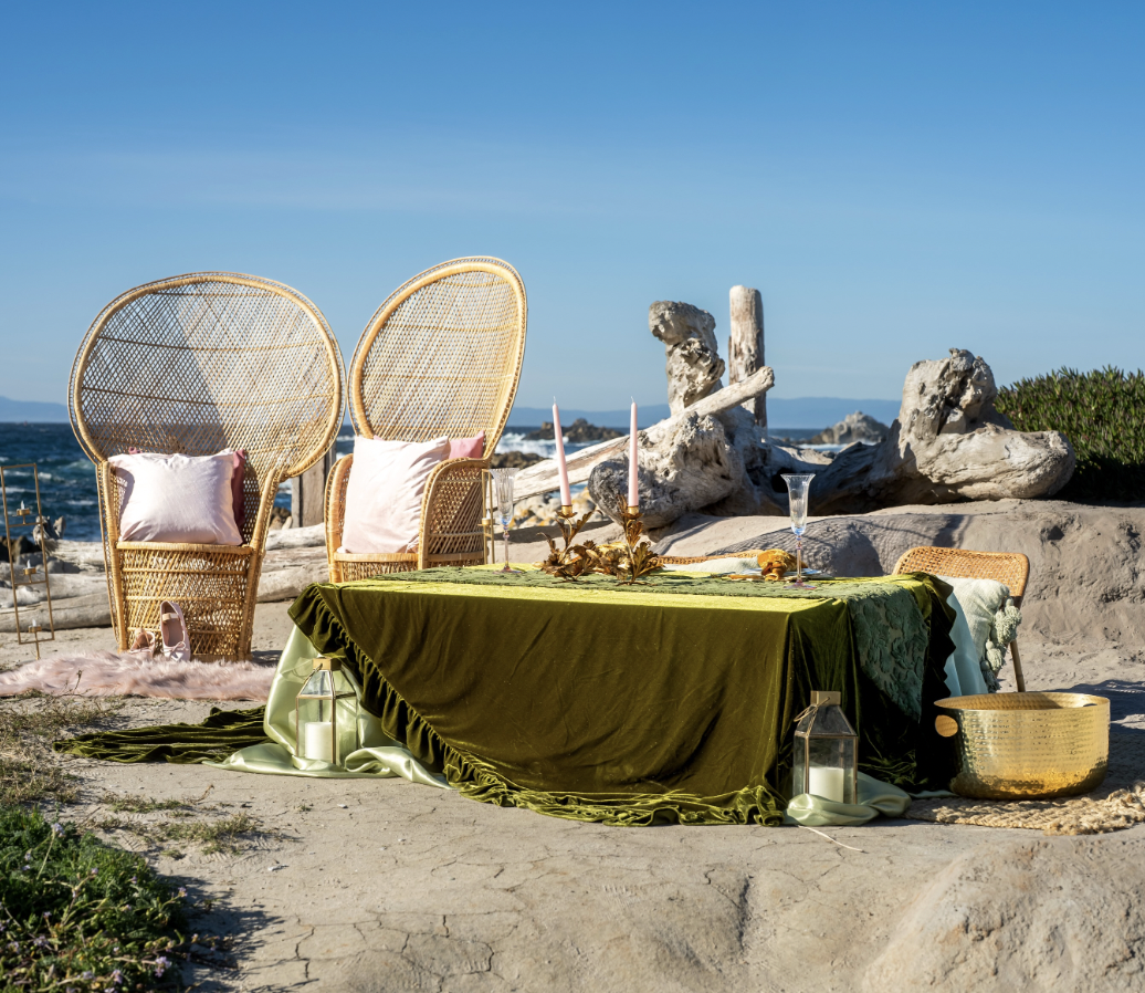 Olive velvet sweetheart table with peacock chairs on a rocky Pacific coastline